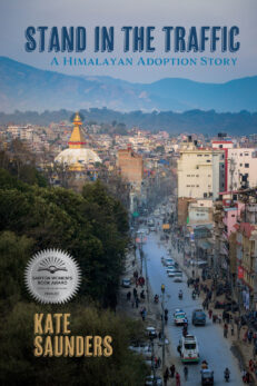 Stand In the Traffic: A Himalayan Adoption Story by Kate Saunders shows a Kathmandu street from a high vantage point. And it displays the Sarton Prize as a finalist in the memoir category