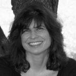 Poet Catherine Smith shares a wide open smile in this black and white photo. She has dark, shoulder-length hair.