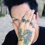 Author Jodi Angel with her tattooed hand half covering her face.