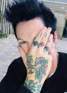 Author Jodi Angel with her tattooed hand half covering her face.