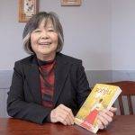 Wondra Chang smiles as she holds a copy of her novel, Sonju.