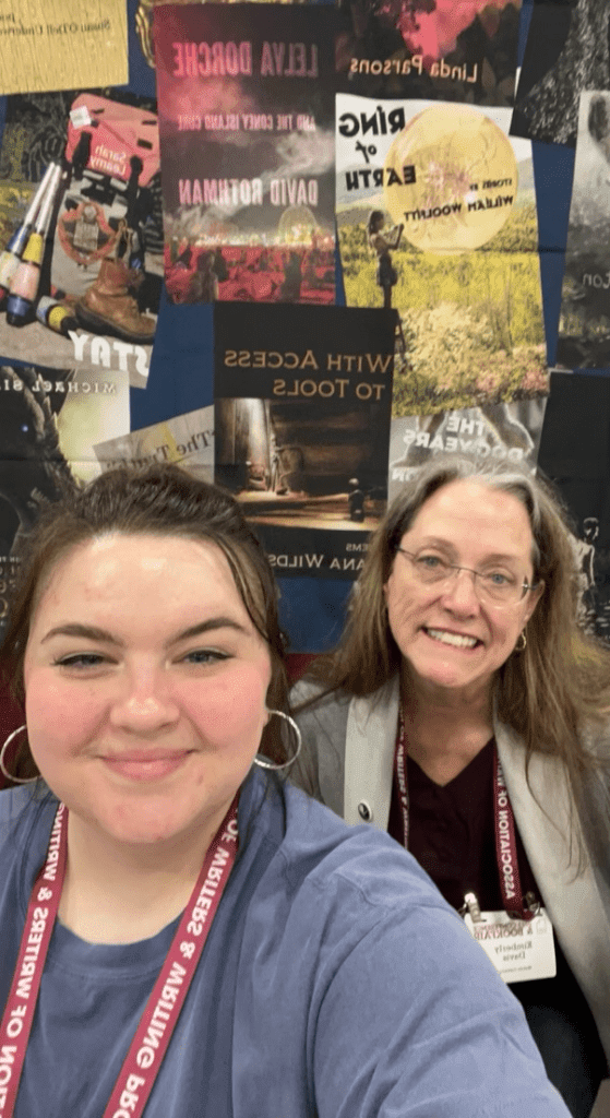 Cat Smith and Madville Publishing founder Kim Davis pose in front of the Madville Publishing booth poster at AWP 2023.