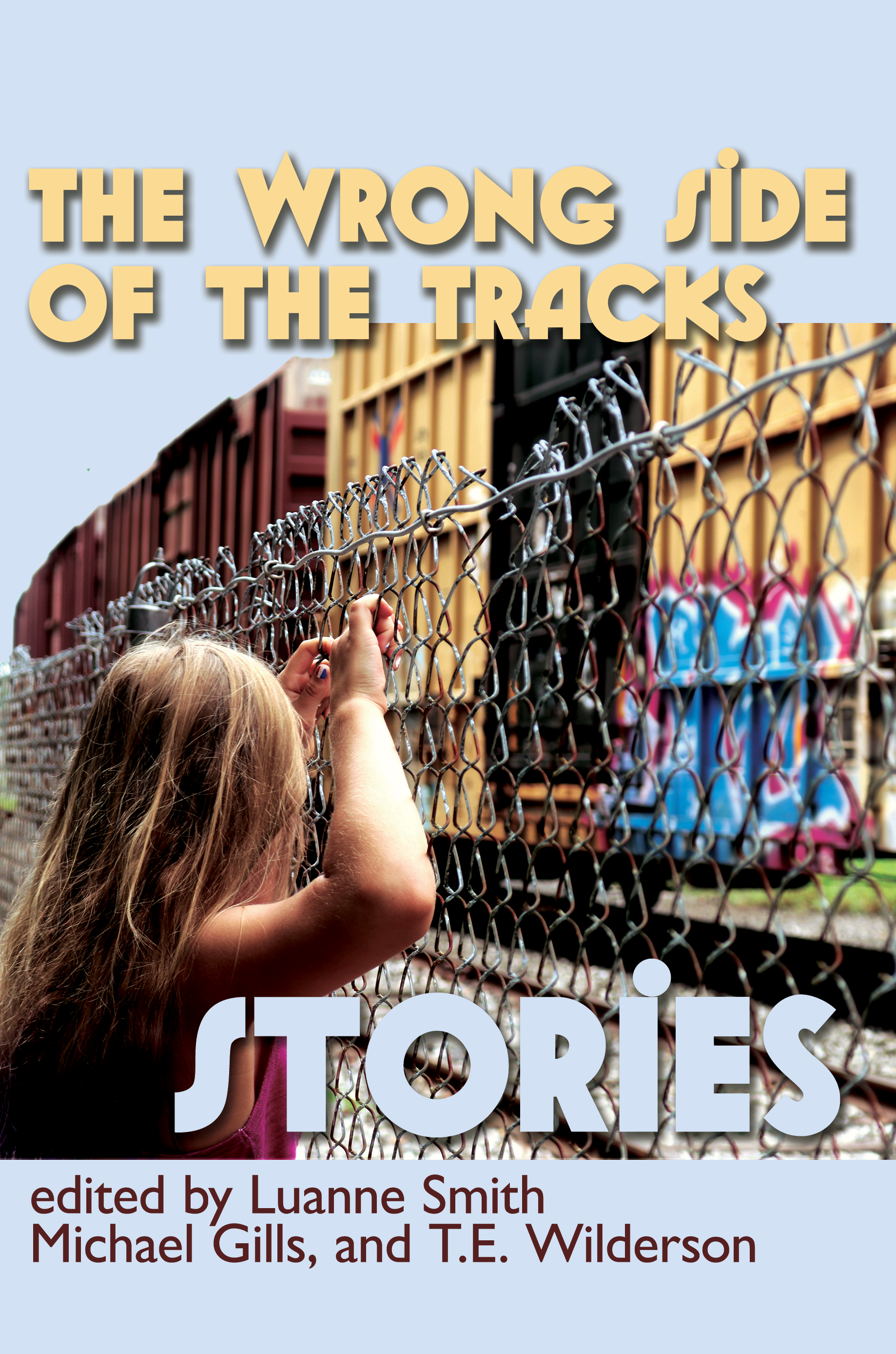 Cover from The Wrong Side of the Tracks: Stories, formerly known as Sticks and Bricks. Cover shows a girl peering through a chain link fence at boxcars sitting on a siding with graffiti painted on their sides.