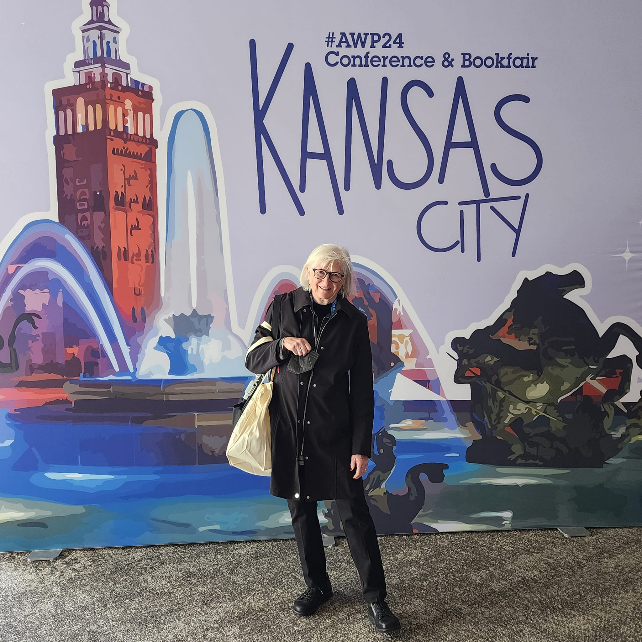 Madville author, Lee Zacharias poses in front of the AWP24 Conference & Bookfair banner in Kansas City.