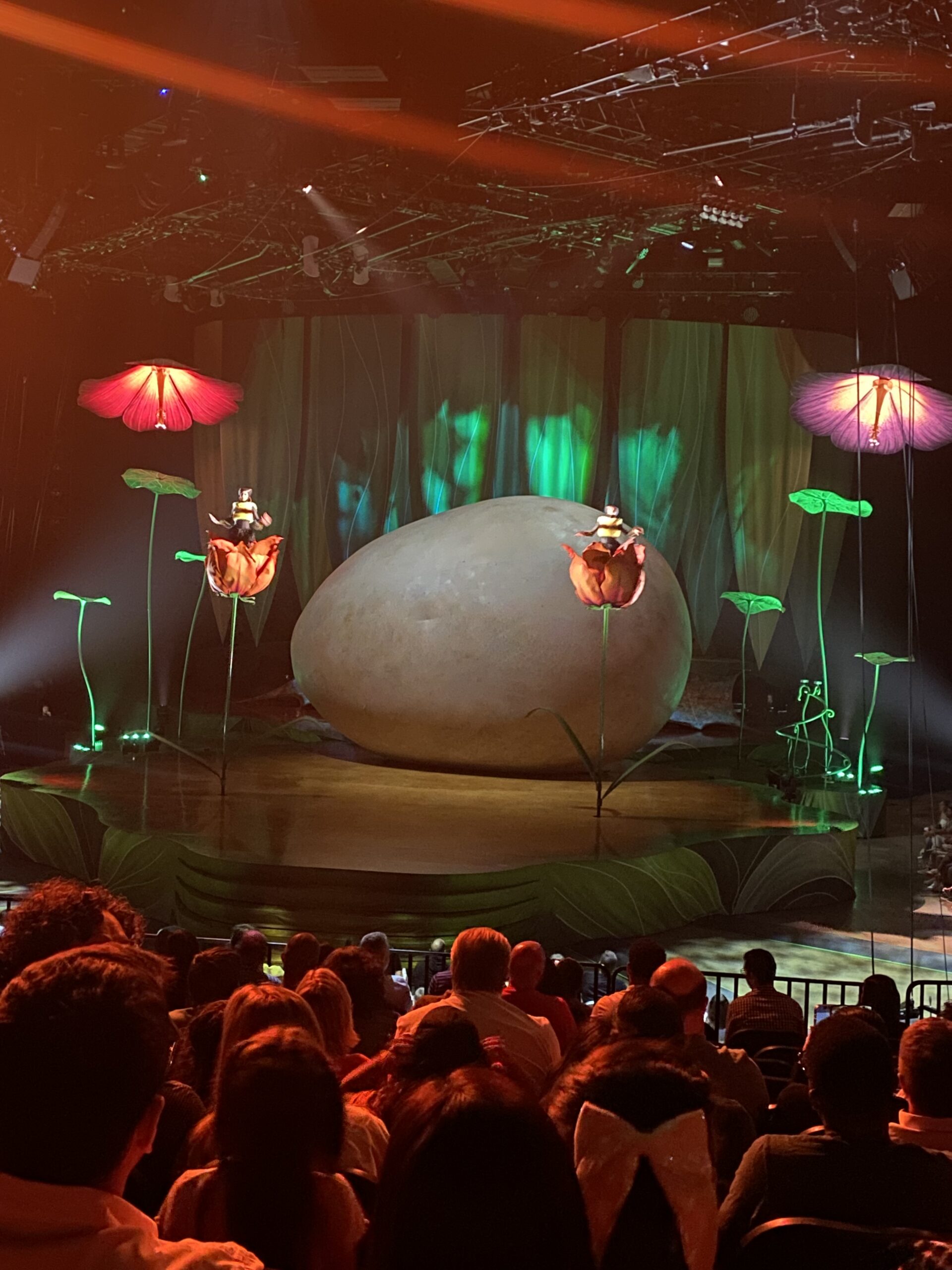 Opening set of the Cirque du Soleil show, Ovo. The audience sees a giant egg that fills the backstage area. Two tall flowers with bees sway under lights that look like hibiscus flowers.