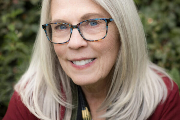 Poet Kari Gunter-Seymour is a white-haired woman with glasses and a lovely warm smile. She's wearing a burgundy-colored sweater.