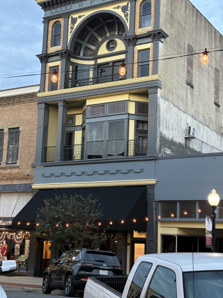 Beautifully restored building in downtown Marshall, Texas. The facad is painted dark blue with gold trim.