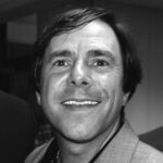 Author Steve Yates... black and white. He is a dark haired man with a suit coat and a dark open-collared shirt. He has a welcoming smile.